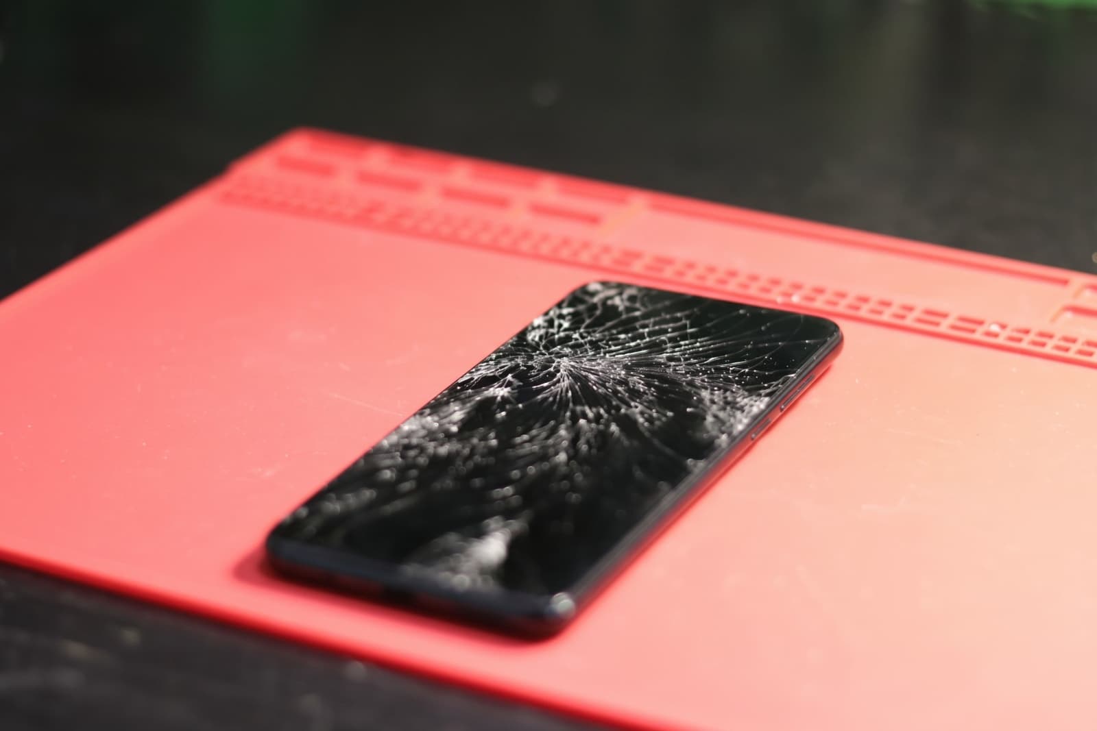iPhone teardown with battery, logic board and screen laid out on the repair bench